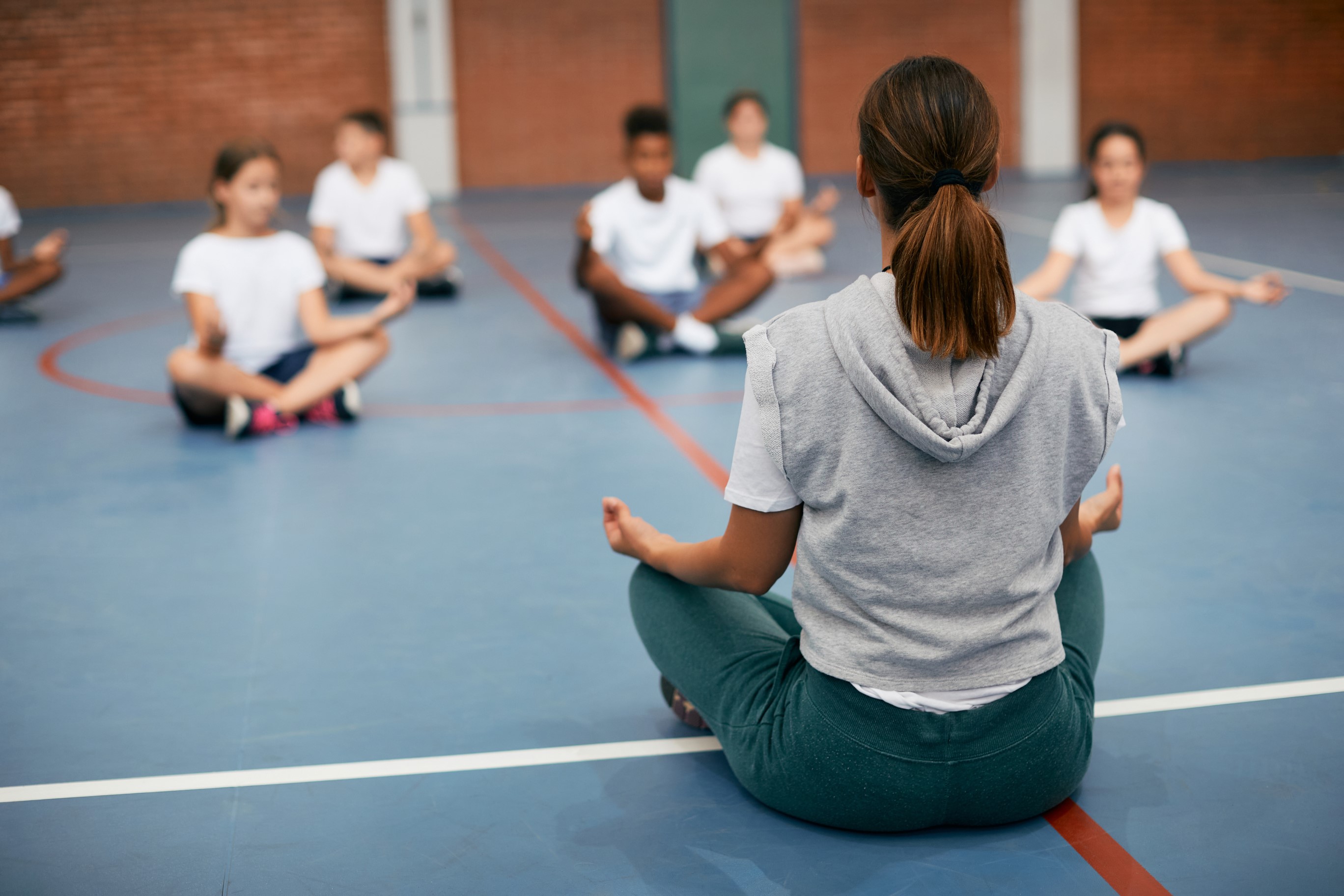 Stock image of an adult instructor leading a yoga class for kids